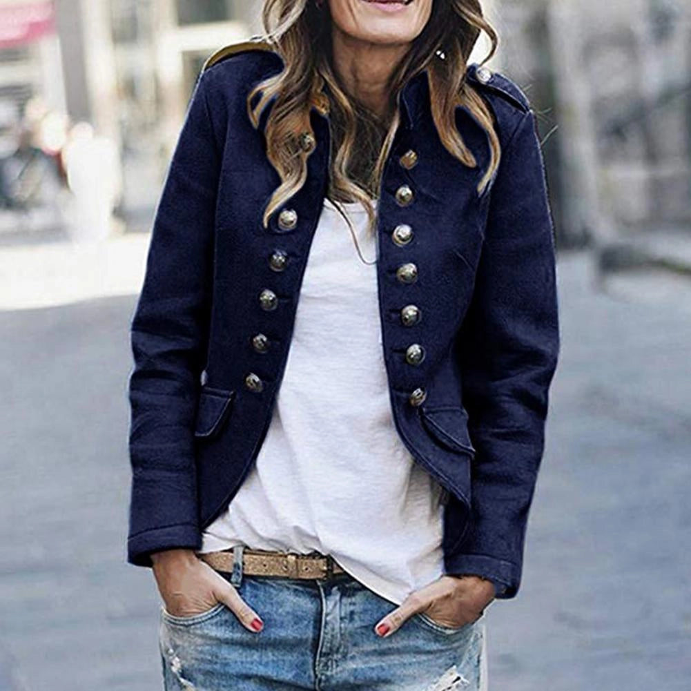 Navy blue double-breasted military style women's blazer with brass buttons, worn by a model standing in jeans and a white dress shirt.